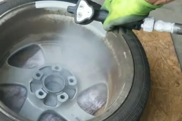 A person cleaning and painting a car wheel