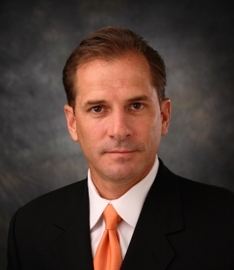 Portrait of a man wearing a suit and orange tie